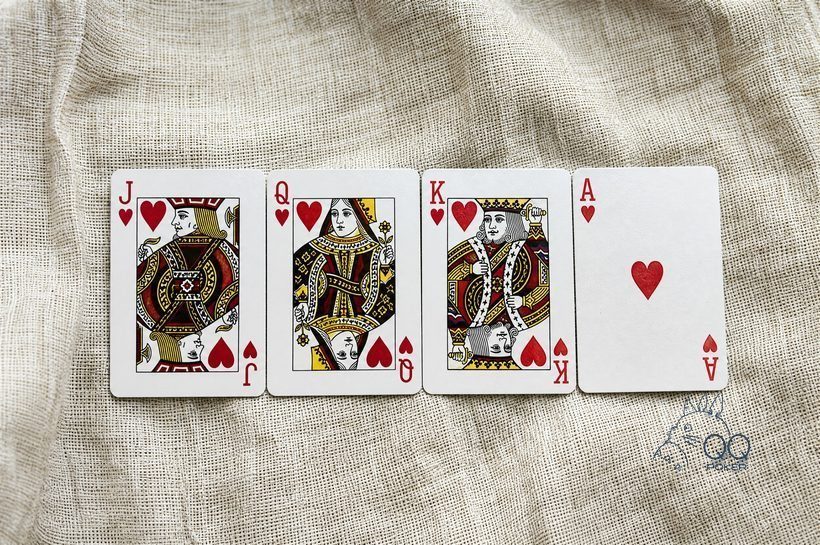 本色亚麻布上四张同花色红桃牌按顺序并排：J、Q、K、A，全部正面朝上